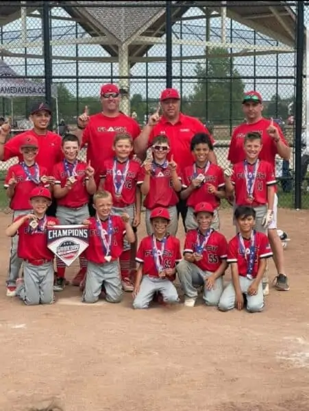9U boys flash baseball team with coaches wearing championship medals and holding a champion home plate for Game Day tournament